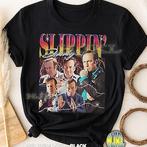 Peut inclure: T-shirt noir unisexe pour adulte avec un graphisme rétro d'un homme dans différentes poses et le texte "Slippin' Jimmy". Le design comprend des éclairs et un fond dégradé coloré.