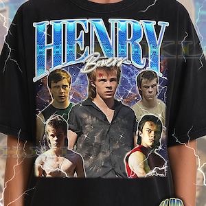 Puede incluir: Camiseta negra unisex para adultos con un diseño gráfico del nombre "HENRY Bowers" en azul, con un diseño vintage. La camiseta incluye imágenes de varias personas. El texto "ADULT Unisex Shirt : BLACK" está en la parte inferior.