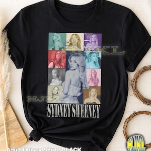 May include: Black adult unisex t-shirt featuring a collage of images of Sydney Sweeney. The design includes a central portrait and several smaller images in various colors. The name "SYDNEY SWEENEY" is printed in white.