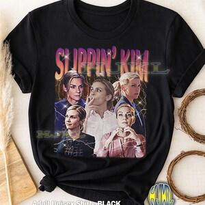 Peut inclure: T-shirt noir unisexe pour adulte avec un graphisme rétro d'une femme et le texte "SLIPPIN' KIM". Le design comprend plusieurs images de la femme avec des éclairs. Le t-shirt est fait d'une matière douce.