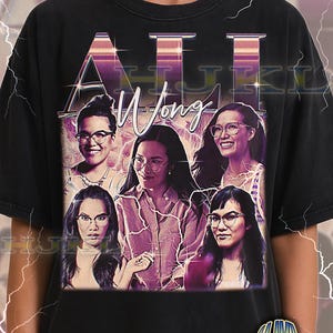 May include: Black adult unisex t-shirt featuring a graphic design with the text "Ali Wong" in a retro style. The design includes multiple portraits of a woman wearing glasses. The shirt has a vintage, worn look.