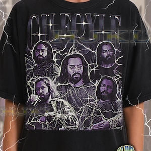 Puede incluir: Camiseta unisex negra para adultos con un gráfico de un hombre con pelo largo y gafas, repetido varias veces. La palabra "CHEROYLE" está impresa encima del gráfico en una fuente estilizada. La camiseta tiene un aspecto vintage.