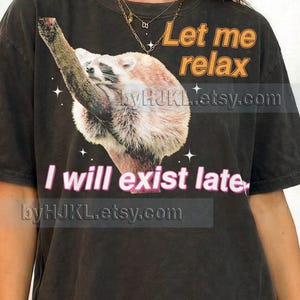 May include: A white ceramic mug with a black handle and the text "But First, Coffee" in a bold, black font. The mug is set against a blurred background, suggesting a cozy setting.