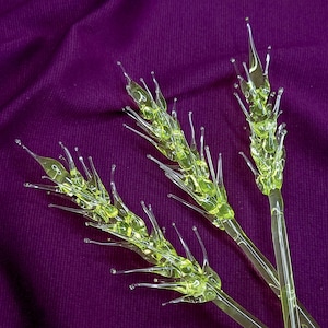 Peut inclure: Trois tiges décoratives fabriquées en verre vert citron translucide, chacune dotée d'une tige centrale avec de multiples protubérances pointues en forme d'aiguilles s'étendant vers l'extérieur pour imiter l'apparence d'épis de blé ou de céréales.