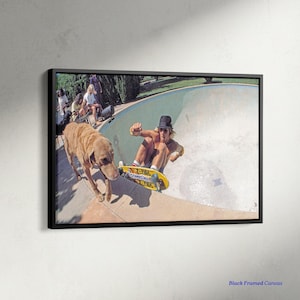 May include: A framed canvas print featuring a vintage skateboarding scene. A person on a yellow skateboard is in a pool, with a dog nearby. The image has a retro aesthetic, with a black frame and the text "Black Framed Canvas".