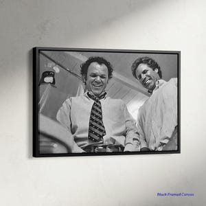 May include: Black and white framed canvas print featuring two men smiling. One man wears a patterned tie and button-down shirt. The other man wears a striped button-down shirt. The text "Black Framed Canvas" is at the bottom.