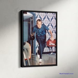 May include: Black framed canvas print featuring a vintage photograph of a man bowling. The man is wearing a blue shirt and dark pants, holding a bowling ball and a red chair. The background includes a patterned wall and a bowling alley.