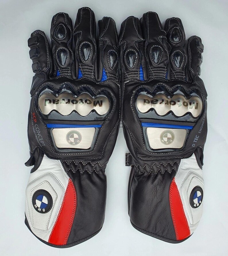 K&ouml;nnte beinhalten: Paar schwarze und wei&szlig;e Motorradhandschuhe mit roten und blauen Akzenten. Die Handschuhe zeigen das BMW-Logo und das Wort "Motorrad". Sie verf&uuml;gen &uuml;ber Schutzpolster und N&auml;hte.