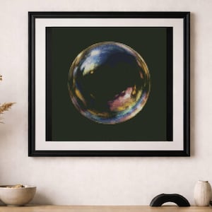 May include: A framed print featuring a colorful bubble against a dark green background. The bubble displays iridescent hues of blue, yellow, and pink. The artwork is displayed above a wooden cabinet with decorative items.