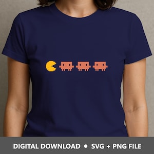 May include: A navy blue short-sleeved t-shirt featuring a pixelated graphic of a yellow circular character facing three orange square-shaped ghost characters. The bottom of the image includes the text: DIGITAL DOWNLOAD • SVG + PNG FILE.