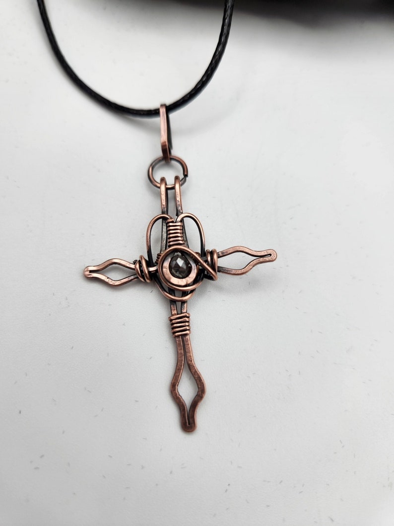 This is a copper Crucifix that has been antiqued in liver of sulfur. It measures almost 2" long and comes with a faux leather cord chain which is 18" long