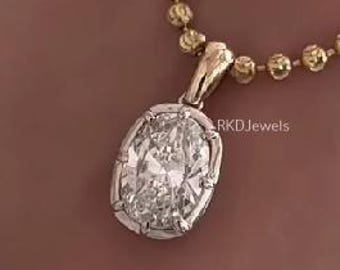 May include: A gold necklace with a pendant featuring a large, oval-shaped diamond. The diamond is set in a gold frame and is the focal point of the necklace. The chain is made of small, round gold beads.