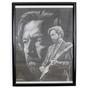 May include: Black framed pencil drawing of a musician playing a guitar. The artwork features a detailed portrait of the musician, with a larger, shadowed face in the background. The artist's signature is visible.