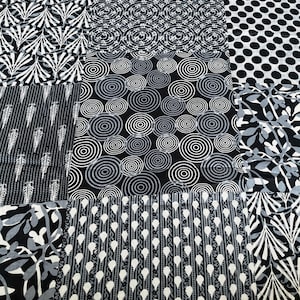 Peut inclure: Un textile patchwork avec divers motifs noirs et blancs. Les motifs comprennent des pois, des cercles concentriques et des motifs floraux et de feuilles stylisés. Le tissu est composé de panneaux rectangulaires avec des motifs contrastés.