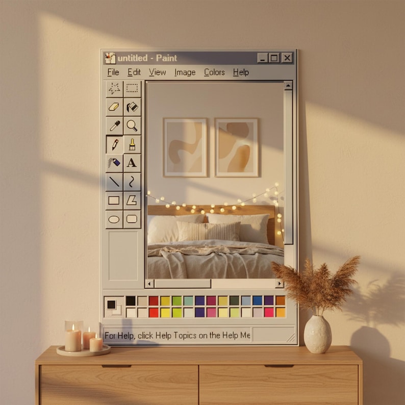 Op de afbeelding: Een decoratieve spiegel ontworpen als de interface van het Windows Paint-programma. De spiegel reflecteert een slaapkamer in neutrale tinten. De tekst "untitled - Paint" staat bovenaan, met een kleurenpalet onderaan. De tekst "For Help, click Help Topics on the Help Me" staat onderaan.