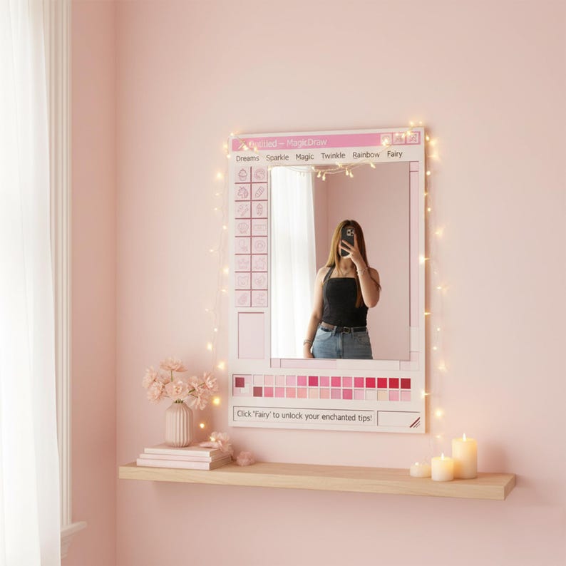 May include: A pink framed mirror with the text "Dreams Sparkle Magic Twinkle Rainbow Fairy" and "Click 'Fairy' to unlock your enchanted tips!". The mirror has a grid of icons and a color palette of pink shades. A person is reflected in the mirror.