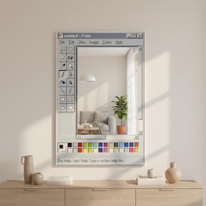 Op de afbeelding: Een rechthoekige spiegel ontworpen om te lijken op de interface van de Windows Paint-applicatie. De spiegel reflecteert een kamer met een bank, plant en raam. De tekst "untitled - Paint" staat bovenaan, met andere tekst en iconen.