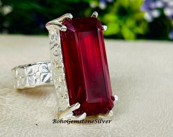Peut inclure: Une bague en argent ornée d'une grande pierre rouge foncé de forme rectangulaire. La bague présente un motif orné sur le corps et autour du sertissage de la pierre. Le texte "BohoGemstoneSilver" est visible.