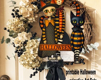 May include: A decorative wreath featuring dried cream-colored flowers, dark berries, and three illustrated cats wearing witch hats and striped clothing. A sign with the text HALLOWEEN is centered, and a black ribbon hangs from the bottom.