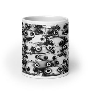Puede incluir: Taza de cerámica blanca con una ilustración en blanco y negro de numerosas caras de extraterrestres de dibujos animados con ojos grandes. El diseño cubre toda la superficie de la taza, creando una estética caprichosa y única.