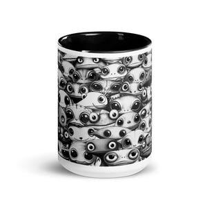 Puede incluir: Taza de cerámica blanca con interior negro. Presenta un patrón repetitivo de criaturas de dibujos animados con ojos grandes en escala de grises. Las criaturas tienen varias expresiones.