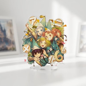 Może przedstawiać: Przezroczysty akrylowy stojak z kolorową ilustracją anime. Obraz przedstawia grupę postaci w strojach i kapeluszach w kolorze turkusowym i złotym, z japońskim tekstem i frazą "Anime coming soon!".