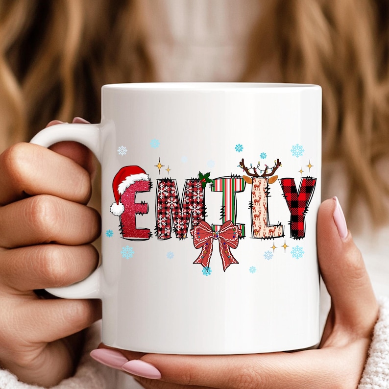 K&ouml;nnte beinhalten: Wei&szlig;e Keramik-Tasse mit dem Namen "EMILY" in einem weihnachtlichen Design. Die Buchstaben sind mit Weihnachtsm&uuml;tzen, Schneeflocken, Karomustern und Rentieren verziert. Eine rote Schleife und Stechpalmenbl&auml;tter vervollst&auml;ndigen das festliche Thema.