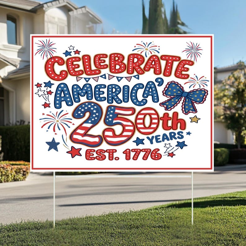 May include: A white yard sign with a red border and the text "CELEBRATE AMERICA 250th YEARS EST. 1776" in red, white, and blue. The design includes fireworks, stars, and a bow, celebrating the anniversary.