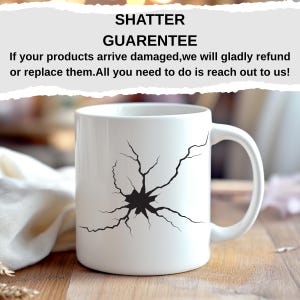 K&ouml;nnte beinhalten: Wei&szlig;e Keramik-Tasse mit schwarzem Shatter-Design. Die Tasse hat einen gebogenen Henkel und der Text "SHATTER GUARENTEE" ist dar&uuml;ber gedruckt. Die Tasse steht auf einer Holzoberfl&auml;che.
