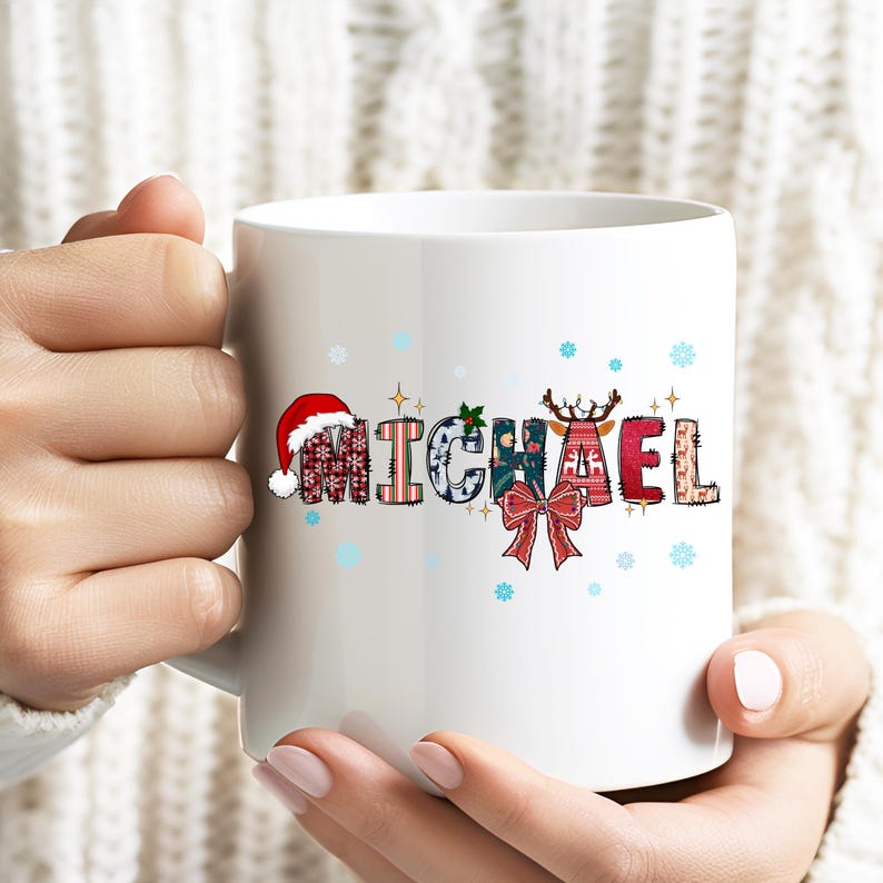 K&ouml;nnte beinhalten: Wei&szlig;e Keramik-Tasse mit dem Namen "MICHAEL" in einem festlichen Patchwork-Design. Die Buchstaben enthalten weihnachtliche Muster, darunter ein Weihnachtsm&uuml;tze, Schneeflocken und ein Rentier. Eine rote Schleife sorgt f&uuml;r einen dekorativen Touch.