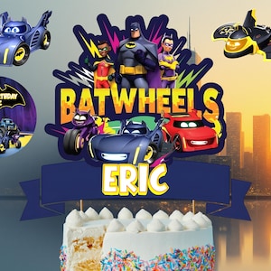 Puede incluir: Un pastel temático de Batwheels, con una pancarta azul con el nombre "ERIC" y un diseño colorido de personajes y vehículos de Batman. El pastel está decorado con glaseado blanco y chispas.
