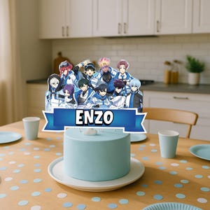 May include: A light blue cake with a decorative topper featuring a group of anime-style characters and the name "ENZO" in white text. The cake sits on a white plate on a wooden table, surrounded by plates, cups, and confetti.
