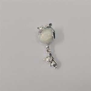 Può includere: Un charm in argento con una perla rotonda di colore chiaro e tre piccole figure di topo. Il charm ha una figura di topo pendente sotto la perla. Il charm è su uno sfondo grigio chiaro.