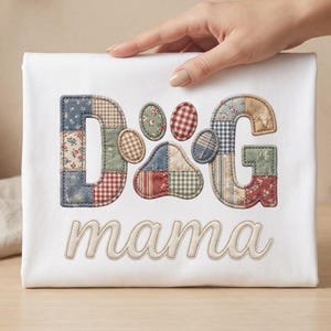 May include: White t-shirt featuring the word "DOG" and a paw print design, with the word "mama" embroidered below. The letters and paw print are made of patchwork fabric in various colours and patterns.