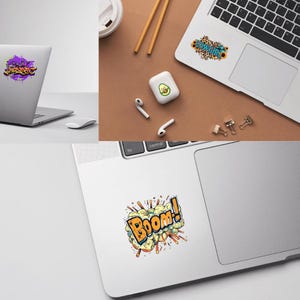 May include: A collection of colorful laptop stickers. One features graffiti-style text, another has the word "Cowgirl" with sunflowers, and a third displays the word "Boom!" in a comic book style.