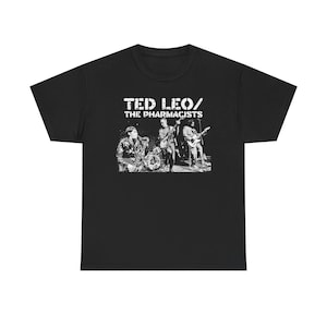 May include: Black t-shirt featuring a white graphic of a band performing on stage. The band's name, "TED LEO / THE PHARMACISTS," is printed above the image in a distressed font. The shirt is made of a soft, comfortable material.