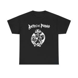 Könnte beinhalten: Schwarzes T-Shirt mit einer weißen Grafik eines Charakters mit Flammen über dem Kopf und dem Text "RATOS DE PORAO" in einer stilisierten Schriftart. Das Design ist mittig auf der Vorderseite des T-Shirts platziert.