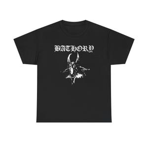 Op de afbeelding: Zwart t-shirt met de bandnaam "BATHORY" in gotisch lettertype. Daaronder een witte illustratie van een gehoornde geitenkop. Het ontwerp is gecentreerd op de voorkant.