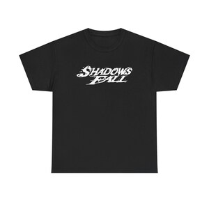 May include: Black t-shirt with the white text "Shadows Fall" in a stylized font across the chest. The shirt is made of a soft material and has a crew neck. This graphic tee is suitable for casual wear.