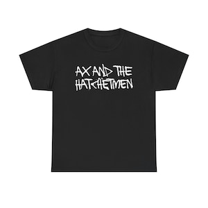 May include: Black t-shirt with the white text "AX AND THE HATchetMEN" across the chest. The text is in a stylized, slightly distressed font. The shirt is a basic crew neck style.