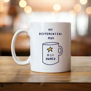 Könnte beinhalten: Weiße Keramiktasse mit dem Text "MY DIFFERENTIAL MUG" in Marineblau. Darunter eine Zeichnung einer Tasse mit einem Stern und dem Text "0,1% OWNED". Die Tasse hat einen weißen Henkel.