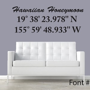 May include: A white couch with a gray wall behind it. The wall has black text that reads "Hawaiian Honeymoon 19° 38' 23.978" N 155° 59' 48.933" W" and "Font #1".