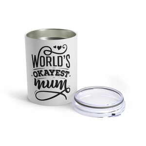 May include: A white tumbler with the text "WORLD'S OKAYEST mum" in black script. The tumbler has a silver interior and a clear lid. The design includes decorative hearts and swirls, perfect for a gift.