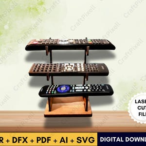 May include: A wooden remote control organizer with three shelves, each holding a different remote. The organizer is made of light brown wood and has a simple, modern design. The image also includes the text "LASER CUT FILE" and "DIGITAL DOWNLOAD".