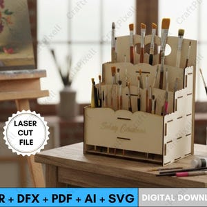 Könnte beinhalten: Ein mehrfach unterteiltes Pinselhalter aus Holz, lasergeschnitten mit dekorativem Design, gefüllt mit Pinseln verschiedener Größen. Der Halter steht auf einem Holztisch, mit Kunstbedarf und einer Staffelei im Hintergrund. Der Text "LASER CUT FILE" ist sichtbar.