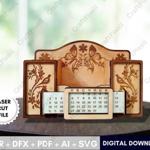 以下が含まれることがあります： 木製の卓上オーガナイザー。カレンダーとフォトフレーム付き。オーガナイザーは、花と鳥のデザインでレーザーカットされています。カレンダーには月の日にちが表示されます。「LASER CUT FILE」の文字が見えます。
