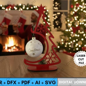 Può includere: Un supporto rosso tagliato al laser per decorazioni natalizie a forma di albero con una palla di Natale bianca. Il supporto per ornamenti ha un design a stella e fiocco di neve. La palla di Natale ha la scritta "Christmas". L'immagine include anche il testo "LASER CUT FILE".