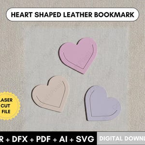 May include: Three heart-shaped leather bookmarks in pink, beige, and lavender. Each bookmark has a contrasting outline. The text "HEART SHAPED LEATHER BOOKMARK" is at the top. A yellow sticker says "LASER CUT FILE".