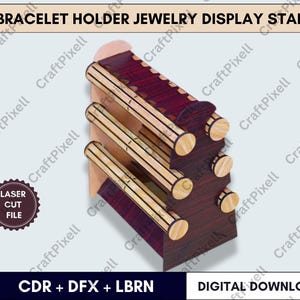 Op de afbeelding: Een houten armbandhouder sieraden display stand. De standaard heeft drie horizontale staven voor het weergeven van armbanden. De standaard is gemaakt van donkerbruin hout met lichtbruine accenten. De tekst "BRACELET HOLDER JEWELRY DISPLAY STAND" staat bovenaan.