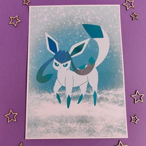 Peut inclure: Une impression représentant une créature blanche et bleue stylisée avec de grandes oreilles et une longue queue, sur un fond bleu clair et blanc. L'œuvre d'art a des accents turquoise et argentés. Des décorations en forme d'étoiles en bois entourent l'impression.